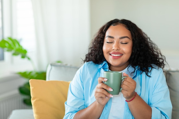 家で味を楽しみながら朝のコーヒーを飲んで幸せな黒人女性