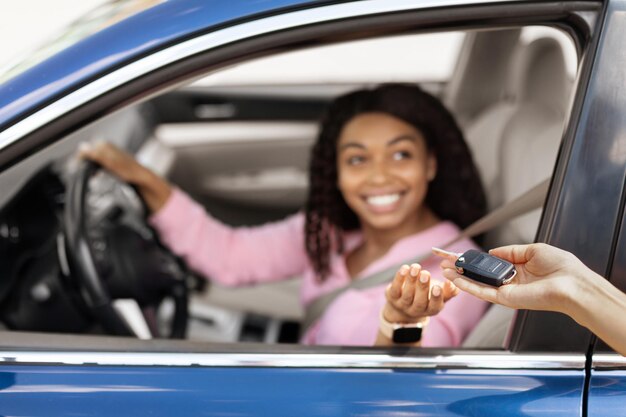 Happy black woman sitting in new car taking keys