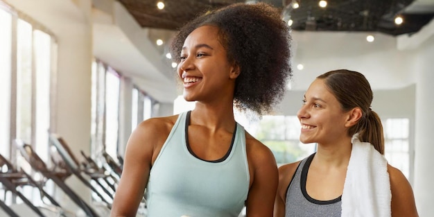 Happy black woman warming up with female friend during sports training in gym center