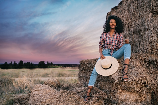 Happy black young woman sitting on a pile of hay