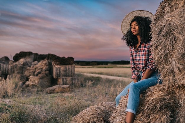 Happy black young woman sitting on a pile of hay