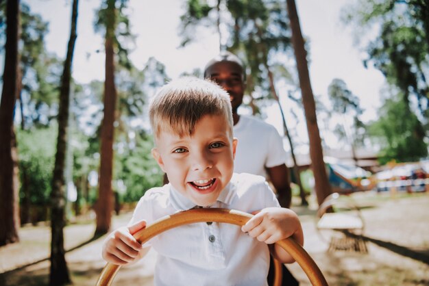 Happy Blond Boy African Man Family Playing Seesaw