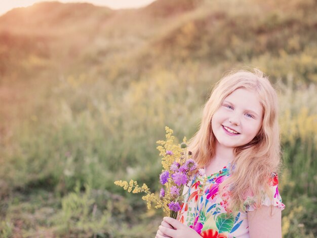 Happy blond girl on meadow at sunset