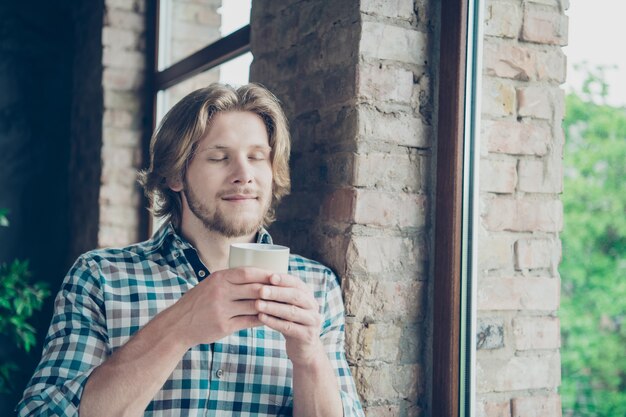 コーヒーとオフィスでポーズをとって幸せなブロンドの男