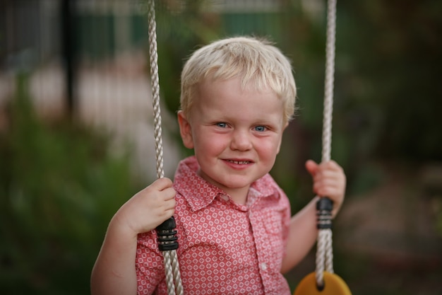 Happy blond hair Australian boy on a swing