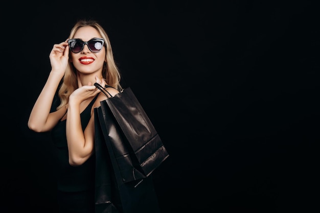 Happy Blonde Boutique Customer in Sunglasses Posing With Purchases