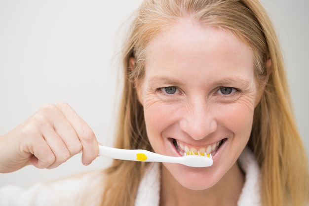 Happy blonde brushing her teeth