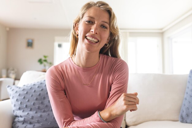 Photo happy blonde caucasian woman having video call and smiling in sunny living room