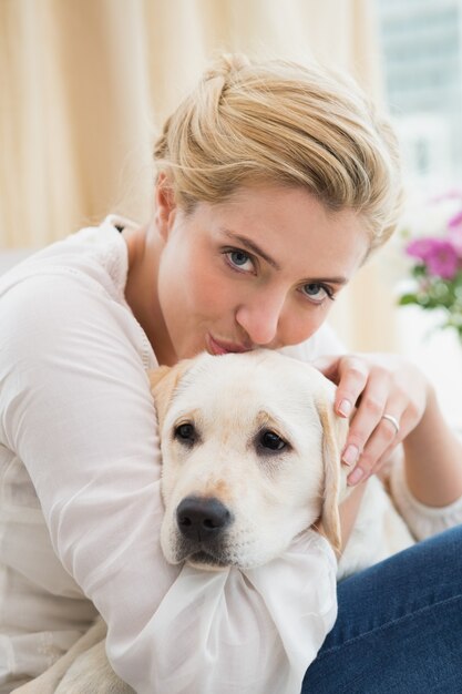 幸せなブロンド、子犬とソファーに抱かれて