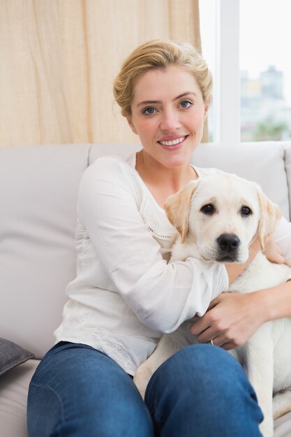 幸せなブロンド、子犬とソファーに抱かれて