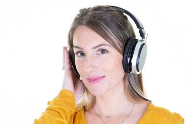 Happy blonde girl listening music in headphones on white