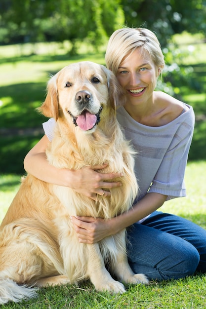 Happy blonde hugging her dog in the park 