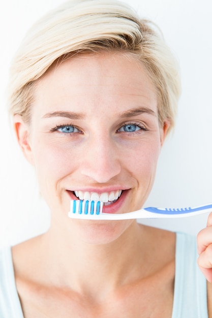 Happy blonde looking at camera holding toothbrush 