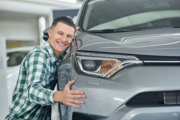 Foto uomo biondo felice che sorride dopo l'acquisto della sua prima automobile.