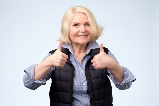 Happy blonde senior woman showing thumbs up