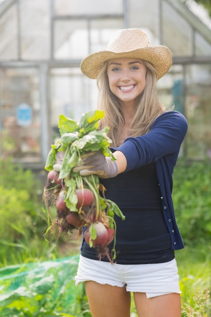 Happy blonde showing home grown vegetables