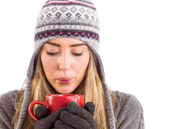 Happy blonde in winter clothes holding mug