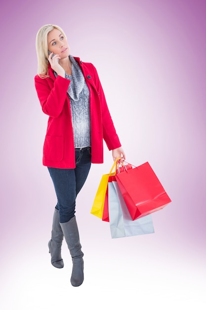 Happy blonde in winter clothes holding shopping bags