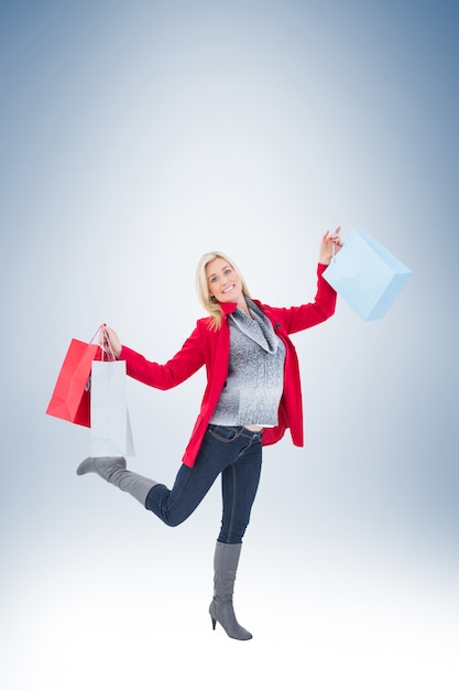 Happy blonde in winter clothes holding shopping bags