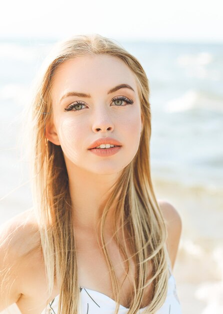 Happy blonde woman in free happiness bliss on ocean beach standing straight and posing