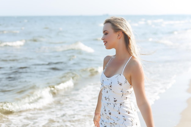 Happy blonde woman in free happiness bliss on ocean beach standing straight and posing.