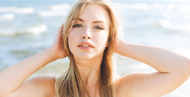 Happy blonde woman in free happiness bliss on ocean beach standing straight and posing