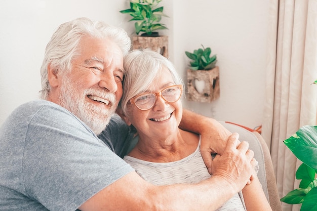 Happy bonding loving middle aged senior retired couple sitting on sofa looking in distance