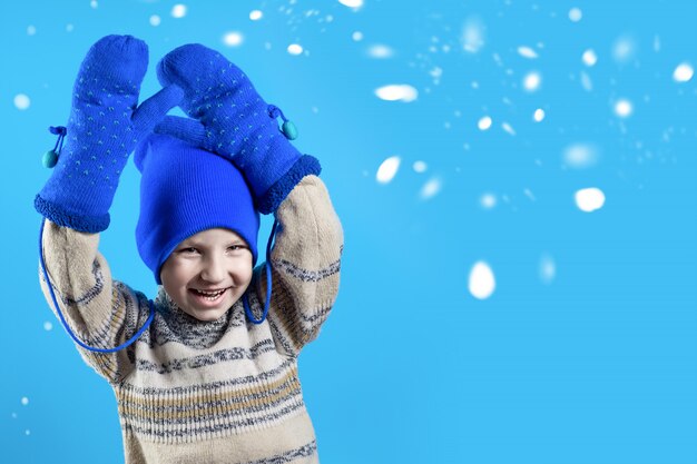 Happy boy in a blue hat, mittens and sweater