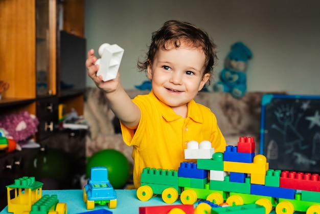 Happy boy child playing at home with colored blocks