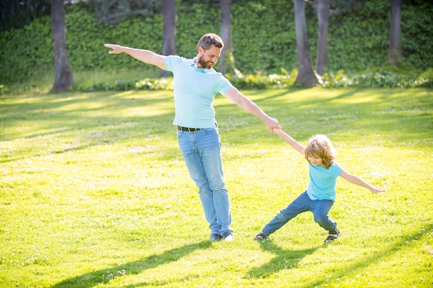 Happy boy child pull fathers hand playing on summer outdoors, fun.