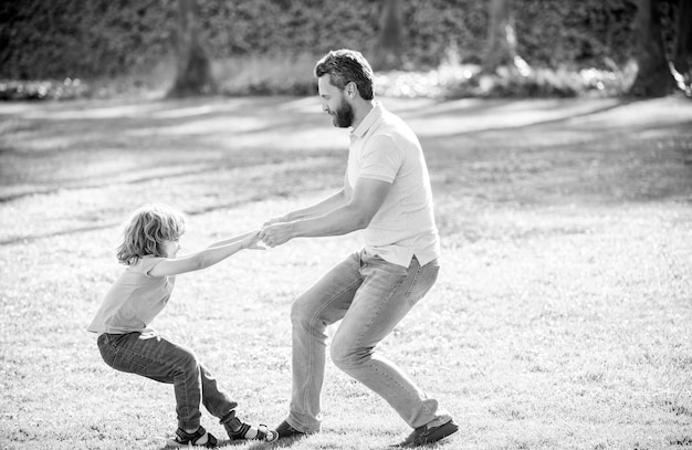 Happy boy child pull fathers hands playing on summer outdoors play