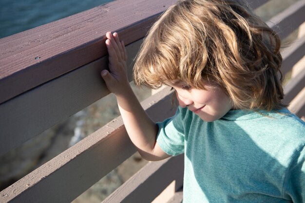 幸せな男の子の子の笑顔は、屋外の手すりの夏、レジャーに立っています。