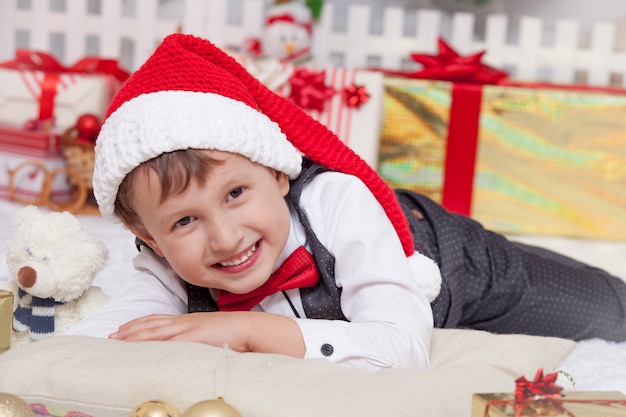 Happy boy in Christmas interior, Santa's cap with gifts