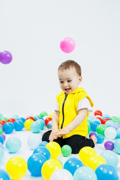 子供の遊び場でカラフルなボールを着た幸せな少年 ボールに隠れた子供の笑顔