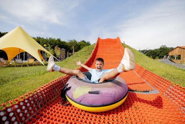 Happy boy descends in inflatable sledding tube at amusement park