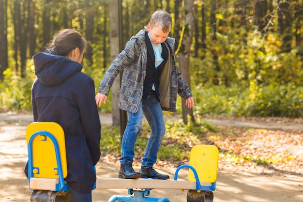 Felice ragazzo e ragazza nel parco giochi al giorno d'autunno.