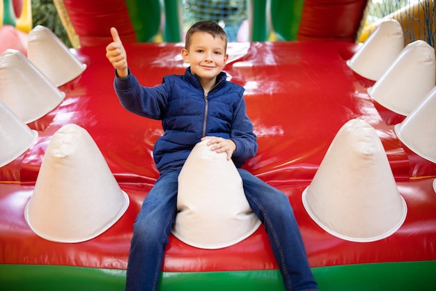 Photo happy boy having a lots of fun on a colorful inflate castle