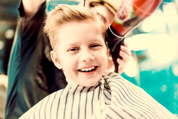 Happy boy during his hair styling in barbershop