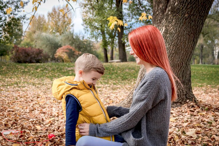 Фотография счастливый мальчик и его мать весело проводят осенний день на природе