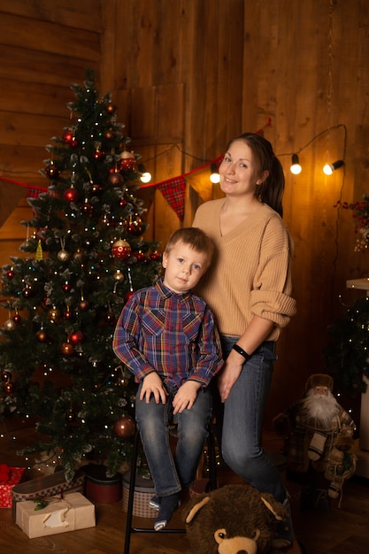 Happy boy and his mother sitting near Christmas tree