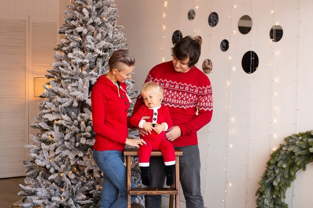 Happy boy and his parents near a Christmas tree.