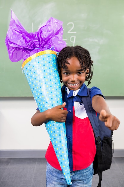 Happy boy holding gift in classroom