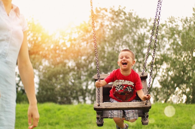 Photo happy boy holding swing in park