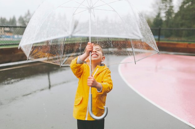 happy boy holding umbrella while standing in sports court