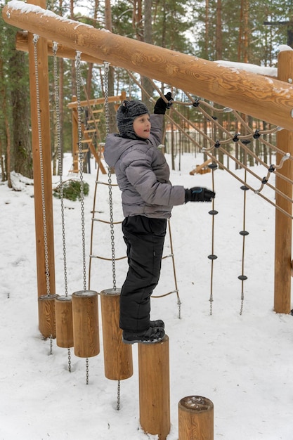 A happy boy is playing on a children39s playground in a winter park