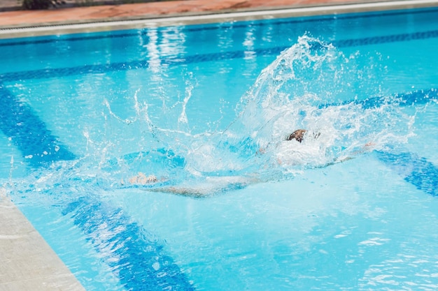 Счастливый мальчик ребенок прыгает в бассейне
