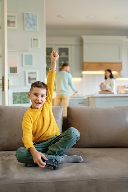 Happy boy kid with joystick playing video computer game at home living room. Leisure time on weekend concept