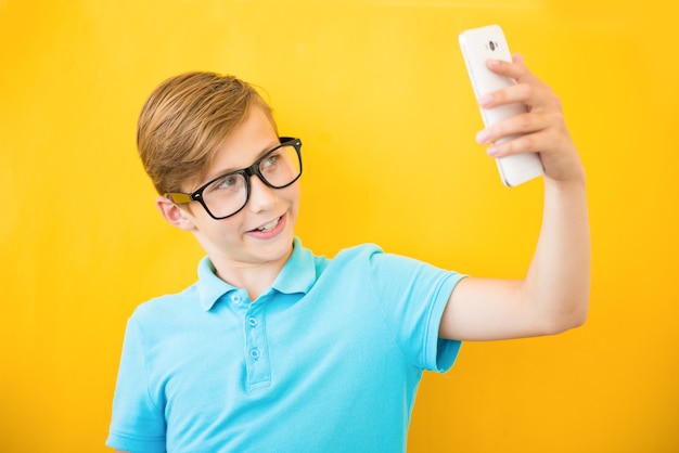 Happy boy making selfie on yellow background