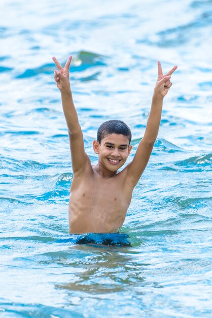 青い海の水で遊んで幸せな少年