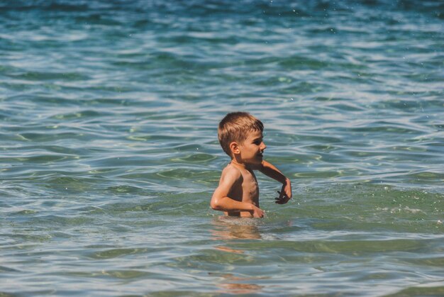 Happy boy playing in sea on sunny day